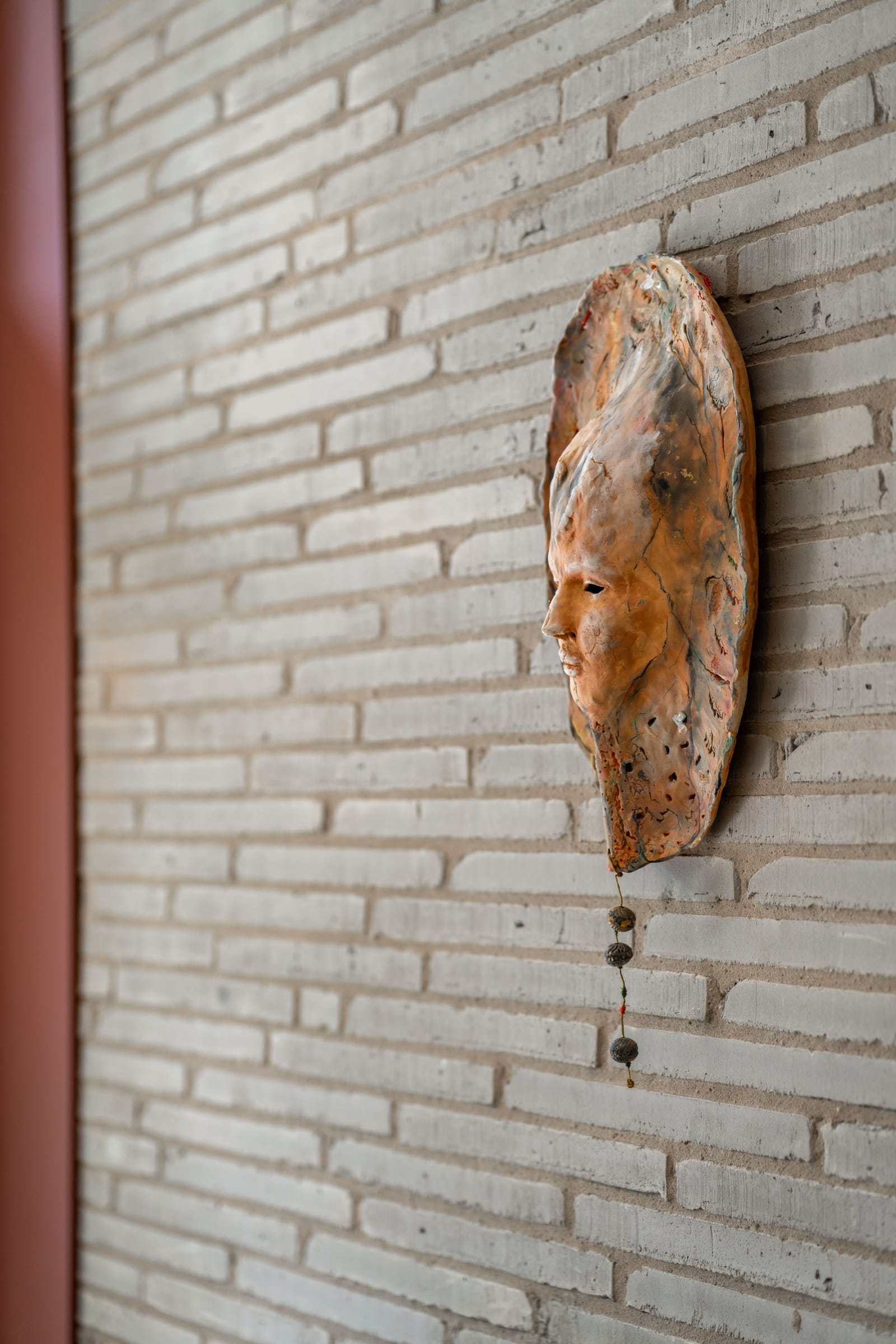 Wooden mask sculpture on a brick wall